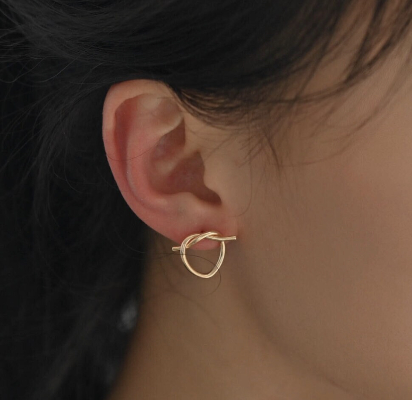 Model wears Wisteria London Lovers Knot Gold Stud Earrings